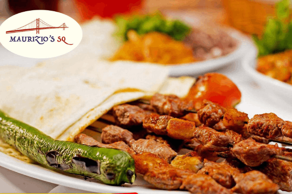 A delicious plate of Maurizio's grilled meat kebabs, with a grilled green pepper and a folded flatbread.